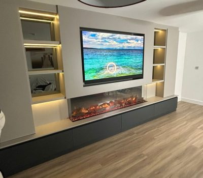 A media wall installation with tv, shelving and fire.